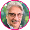 Portrait of an older man with gray hair, glasses, and a mustache, wearing a suit jacket, shown in a circular frame with a blurred outdoor background—an image that evokes trust and expertise in fraud prevention.