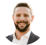 A man with short hair and a beard, wearing a suit jacket and white shirt, smiling at the camera against a light background—raising questions about online identity in the age of deepfake technology.