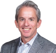 Smiling man with gray hair, wearing a gray blazer over a striped shirt, poses confidently in front of a white background, representing Memcyco at RSA Conference 2025.
