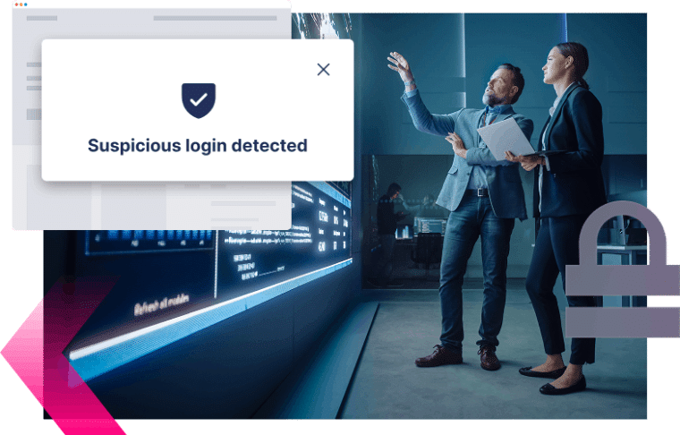 Two people in business attire review data on a large digital screen, discussing a MiTM attack after a notification overlay states "Suspicious login detected.