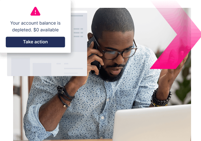 A man on the phone looks at his laptop with concern. A pop-up warns, "Your account balance is depleted. $0 available. Take action now to stop more ATOs.