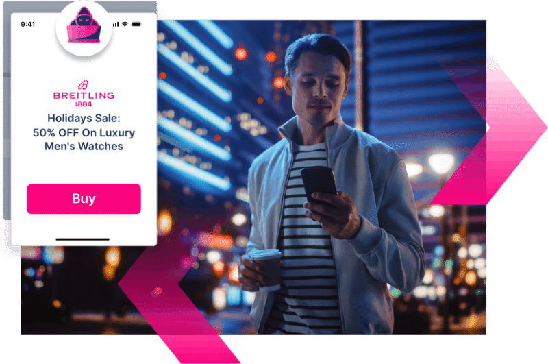 A man stands outdoors at night in a city, holding a coffee cup and looking at his phone. An online ad offers 50% off luxury men's watches from Breitling—reminding him to stay alert for scams and use Digital Impersonation protection.