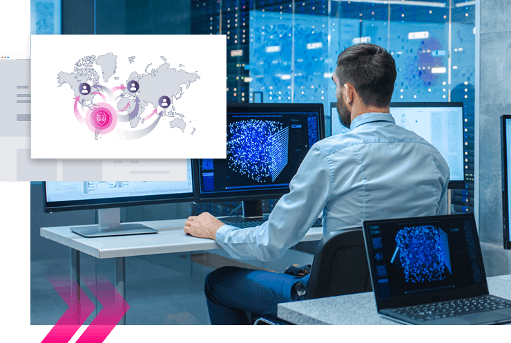 A man sits at a desk in a modern office, viewing data visualizations on multiple monitors—one screen highlights Digital Impersonation protection with a graphic of a global network.